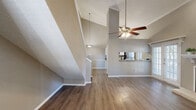 This two-story home offers a thoughtfully designed layout spread across two floors, providing comfortable and functional living spaces throughout. The main floor greets you with a welcoming entrance that opens into a bright, open-concept living room and kitchen area. The living room is a standout, boasting dramatic vaulted ceilings with a ceiling fan, rich hardwood-style flooring, built-in display shelving, and a classic fireplace with a white mantle. French doors flood the space with natural light and offer outdoor access. The kitchen is well-appointed with white cabinetry, granite-style countertops, a decorative tile backsplash, stainless steel appliances, and a pendant light fixture, all complemented by a window that brings in additional natural light. Upstairs, the primary bedroom is a generous retreat featuring plush carpeting, a ceiling fan, and an en-suite bathroom with white vanity cabinetry, a large mirror, and a dedicated closet with built-in shelving and hanging rods. A second bedroom with carpet and ceiling fan provides additional flexibility, while two additional bathrooms ensure convenience for residents and guests alike. Two closets offer ample storage throughout the home.