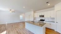 Located at 1298 Mabry Street in Lawrenceville, GA, this two-story home offers four bedrooms, four bathrooms, and a well-organized layout across two floors. The main level features an open-concept kitchen and living area finished with light hardwood-style flooring throughout. The kitchen is equipped with white shaker cabinetry, a subway tile backsplash, granite countertops on a central island with a sink, and a full suite of stainless steel appliances including a refrigerator, range, and over-the-range microwave. The living area benefits from natural light through multiple windows and is fitted with a ceiling fan. The upper floor houses all four bedrooms, each carpeted and featuring ceiling fans and windows that bring in natural light. The generously sized primary bedroom includes a dedicated bathroom with a glass-enclosed tiled shower and walk-in closet with wire shelving. Additional bedrooms are served by their own closets and share access to the remaining bathrooms. A bright hallway connects the upper-level rooms, featuring hardwood-style flooring and a staircase with railing. A dedicated laundry room with full-size washer and dryer hookups and overhead shelving adds practical convenience to the home's functional design.