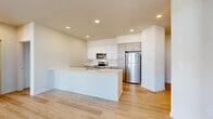 Located in Marysville, WA, this well-appointed 3-bedroom, 2-bathroom residence offers a thoughtfully designed single-level layout. The open-concept kitchen and living area serves as the heart of the home, featuring a large center island with a white quartz countertop and undermount sink, sleek white upper cabinetry complemented by warm wood-toned lower cabinets, and a full suite of stainless steel appliances including a refrigerator, electric range, and microwave. Light wood-style flooring flows seamlessly throughout the entire residence, lending warmth and visual continuity to every room. The spacious primary bedroom is a standout feature, boasting dramatic vaulted ceilings and large picture windows that frame neighborhood and treetop views while flooding the room with natural light. A dedicated closet provides generous storage with built-in wire shelving. The primary bathroom includes a wide vanity with quartz countertops, wood-grain cabinetry, and an adjacent open shelving closet for additional storage. The secondary bedrooms are bright and well-proportioned, each with clean neutral walls and continued wood flooring. A sliding barn-style closet door accents one of the secondary bedrooms. The living area features a private exterior door with access to a balcony, offering an inviting indoor-outdoor connection.