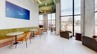This 352 square meter single-story commercial space in Ottawa combines industrial and contemporary design elements to create a bright, welcoming environment. The open floor plan is characterized by high ceilings with exposed ductwork and beams, painted in a light green that adds a fresh, modern touch. Large floor-to-ceiling windows flood the space with natural light and offer views of the surrounding area.

The interior features a mix of textures and materials, including polished concrete floors, white brick walls, and vibrant teal tilework. A curved reception desk with teal tiling serves as a focal point near the entrance. Various seating areas are scattered throughout, featuring a combination of modern and mid-century inspired furniture in earthy tones like olive green, burnt orange, and deep brown.

The space includes several functional areas, such as a bar-height wooden table with stools, comfortable lounge seating, and more private nooks for quiet work or conversations. Colorful artwork and motivational posters add personality to the white walls. The elevator area is well-lit and features inspirational text on the walls.

This versatile space appears suitable for a variety of commercial uses, from a modern office to a co-working space or creative studio. Its design encourages collaboration while also providing areas for focused work, making it adaptable to different needs and work styles.
