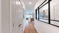 This 2-bedroom, 2-bathroom residence offers a clean, modern aesthetic across a single floor. A welcoming entry hallway with warm hardwood flooring and a bold black-framed accent window leads into the open living and kitchen area. The kitchen features a central island with warm wood cabinetry and pendant lighting, flowing seamlessly into the bright living room. The living room is highlighted by large windows with outdoor views, hardwood floors, and ample natural light. Both bedrooms are carpeted and feature ceiling fans, large windows, and dedicated closets. The spacious primary bedroom comfortably accommodates a king-sized bed and provides a serene retreat. The second bedroom is equally well-proportioned with generous natural light. Each bathroom is finished with warm wood vanity cabinetry, stone-toned countertops, and hardwood-style flooring. The primary bath includes a glass-enclosed walk-in shower, while the second bath offers a full tub-shower combination with white subway tile surround. Throughout the residence, the consistent use of neutral tones, natural materials, and modern fixtures creates a cohesive and inviting atmosphere well-suited for comfortable everyday living.