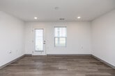 Located on Mission Circle in Waterloo, Iowa, this single-floor, three-bedroom, two-bathroom home offers a clean, modern design with a bright and open feel throughout. Light wood-tone flooring runs consistently across the living areas and bedrooms, complementing the crisp white walls and creating a cohesive, airy atmosphere.

The kitchen is a standout feature, showcasing white shaker-style cabinetry with ample upper and lower storage, stone-look countertops, a central island with a marble-patterned surface, black appliances including a range and refrigerator, and recessed lighting overhead. In-unit laundry is conveniently situated in the same open area as the kitchen, adding practical functionality.

The living area benefits from natural light through windows and a glass-panel exterior door, maintaining the home's bright and welcoming character. Each of the three bedrooms features the same light wood flooring and windows that allow for natural light and outdoor views, with five closets distributed throughout the home providing generous storage.

The two bathrooms are well-appointed with stone-topped vanities, wood-tone flooring, and brushed nickel hardware. One bathroom includes an accessible layout with stainless grab bars and open floor space, while the second offers a full tub-shower combination. The home's thoughtful, modern finishes make it a comfortable and functional living space.