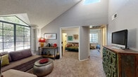 This well-designed 2-bedroom, 1-bathroom single-story home makes efficient use of its compact footprint through a thoughtful open-concept layout. The living room is an architectural standout, featuring soaring vaulted ceilings that create a strong sense of openness, complemented by a large triangular picture window that frames outdoor tree views and floods the space with natural light. A skylight above further enhances the bright, airy ambiance. Soft carpet anchors the living area, which flows directly into the adjacent kitchen and dining space, where warm hardwood flooring, white cabinetry, a full suite of white appliances, and ample counter and storage space create a clean, functional environment. Both bedrooms are carpeted and well-proportioned, each benefiting from windows with exterior views and louvered shutters. The primary bedroom includes a dedicated closet and a built-in vanity area, while the second bedroom features elegant pendant lighting. A shared full bathroom offers a tub/shower combination, a wide vanity with integrated sink, and a large mirrored medicine cabinet. Two closets provide additional storage throughout the home. The overall design balances practicality with architectural character, making efficient and comfortable use of the available space.