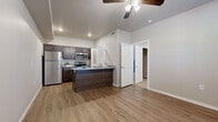 This well-designed one-bedroom, one-bathroom unit at 2600 Longhills Rd E in Benton, Arkansas offers a functional and modern layout across a single floor. The open-concept living and kitchen area is anchored by a peninsula with granite countertops, a built-in sink, and generous prep space. The kitchen is equipped with dark espresso cabinetry, stainless steel appliances including a refrigerator, microwave, and range, and continues the granite countertop theme throughout. Vaulted ceilings and ceiling fans in both the main living area and bedroom enhance the sense of openness, while wood-style plank flooring throughout the common areas adds warmth and durability. The bedroom is carpeted for comfort and features a ceiling fan, a window with natural light, and direct access to a dedicated closet. The bathroom is cleanly appointed with a dark wood vanity, round mirror, and hardwood-style flooring. A laundry area accommodates a top-loading washer alongside a water heater, adding everyday convenience. Neutral tones and clean finishes throughout create a cohesive, move-in-ready atmosphere well-suited for comfortable single-occupant living.