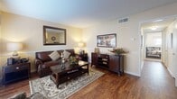 Located at 10580 Hammerly Blvd in Houston, TX, this single-story 2-bedroom, 2-bathroom residence offers a practical and comfortable layout designed for everyday living. The living room serves as the heart of the home, featuring warm wood-look flooring, neutral wall tones, and a window with natural light that creates an inviting atmosphere. The space flows seamlessly into a dedicated dining area, highlighted by a pendant light fixture and direct access to the kitchen.

The galley-style kitchen is efficiently designed with white cabinetry, dark granite-style countertops, a stainless steel double sink, tile backsplash, and black appliances including a refrigerator and range. Ample cabinet storage lines both walls, maximizing functionality.

Both bedrooms are carpeted and generously sized, each equipped with a ceiling fan and natural light from windows. Each bedroom is paired with its own bathroom, both featuring white vanity cabinetry, dark countertops, large mirrors, and overhead lighting — providing privacy and convenience for residents.

Throughout the home, the consistent use of wood-look flooring in common areas and warm, neutral paint tones creates a cohesive and welcoming aesthetic, making this a well-rounded residential space ideal for comfortable daily living.