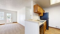 Located on White Swan Drive in Greece, NY, this two-bedroom, one-bathroom single-floor residence offers a practical and well-organized layout. The open-concept kitchen flows directly into the combined dining and living area, creating a connected and functional living space. The kitchen is equipped with warm-toned wood cabinetry lining both walls, black appliances including a gas range and refrigerator, a double sink, and a dishwasher. Light wood-look flooring runs through the kitchen and bathroom, while soft neutral carpet covers the living and bedroom areas.

The living room receives natural light through a sliding glass door, adding a bright and open feel to the space. Both bedrooms are carpeted and feature windows with blinds that allow for natural light. The primary bedroom is generously sized and includes access to a walk-in closet with shelving. Additional closets throughout the unit provide ample storage.

The bathroom is clean and functional, featuring a vanity with mirror cabinet, a toilet, and a tub-shower combination, all finished with wood-look flooring. A dedicated laundry area adds everyday convenience. With three closets total and a straightforward, efficient layout, this residence offers practical living in a well-maintained Greece, NY community.