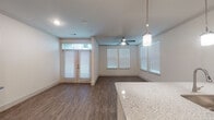 This single-floor residence offers a thoughtfully designed open-concept layout that seamlessly connects the kitchen, dining, and living areas. The kitchen is a standout feature, outfitted with rich dark-espresso cabinetry, granite countertops, and a full suite of stainless steel appliances, including a refrigerator, range, built-in microwave, and dishwasher. A peninsula with a sink and pendant lighting above serves as a natural divider between the kitchen and the main living space, adding both function and style.

The living area is bright and welcoming, benefiting from multiple windows dressed with white blinds that allow ample natural light to filter in. A ceiling fan overhead provides comfort, while French doors with a transom window open to the exterior, enhancing the airy feel of the space. Wood-style flooring runs consistently throughout the main areas, adding warmth and visual continuity.

The bedroom is generously proportioned, featuring corner windows on two walls, a ceiling fan, and the same wood-style flooring. The bathroom includes a full tub-shower combination with tile surround and a curved curtain rod, complemented by the matching dark cabinetry. A well-lit entry hallway connects the main spaces efficiently, completing this clean and contemporary residence.
