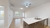 Located at 255 Cemetery Rd in Troy, NY, this thoughtfully designed 2-bedroom, 1-bathroom home offers a clean, modern aesthetic throughout its single-floor layout. The open-concept living and kitchen area serves as the heart of the home, featuring light hardwood-style flooring, crisp white walls, and a ceiling fan with integrated lighting. A wall-mounted mini-split unit provides efficient climate control. Sliding glass doors and large windows flood the space with natural light and lead to an outdoor deck overlooking a lush, wooded backdrop.

The kitchen is outfitted with warm wood-toned cabinetry, a white quartz peninsula with an undermount sink, and a full suite of stainless steel appliances, including a range, microwave, and refrigerator. The spacious primary bedroom features hardwood-style flooring, a wall-mounted HVAC unit, and a large window with outdoor views, while a dedicated walk-in closet provides ample built-in wire shelving for storage. The second bedroom is carpeted and comfortably sized with its own window and closet access. The full bathroom includes a tub/shower combination, a vanity with cabinetry, and light wood-tone flooring, completing this well-appointed home.