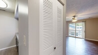 Located in West Lafayette, Indiana, this single-floor, 2-bedroom, 2-bathroom unit offers a practical and well-organized layout. The living room serves as the centerpiece of the space, featuring durable hardwood-style flooring, a ceiling fan with light fixture, and a sliding glass door that opens to a private balcony, filling the room with natural light and outdoor views.

The galley-style kitchen flows directly from the living area and is equipped with dark espresso cabinetry, granite-style countertops, black appliances including a refrigerator, electric range, microwave, and dishwasher, as well as a double-basin stainless steel sink. Wood-look flooring continues throughout the kitchen and hallway.

Both bedrooms are carpeted and feature neutral wall tones, textured ceilings, and dedicated walk-in closets with built-in shelving and hanging rods. The primary bedroom offers a comfortable, functional footprint. Each bedroom is served by its own full bathroom, both featuring tiled tub-shower combinations, wood-look flooring, and vanities with ample cabinet storage.

A hallway with a louvered storage closet connects the main living areas to the bedrooms, contributing to the unit's efficient and cohesive layout.