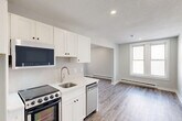 This 320 square foot studio apartment, located at 726 Franklin St in Worcester, MA, offers a thoughtfully designed living space on a single floor. The open-concept layout maximizes the available area, seamlessly blending the living room and kitchen. The living area is illuminated by large windows, providing natural light and views of the surrounding neighborhood.

The kitchen, while compact, is equipped with modern appliances including a stove and refrigerator. White cabinetry lines the walls, offering ample storage space. The bathroom features a full-sized tub-shower combination, toilet, and vanity, finished in crisp white for a clean, contemporary look.

Throughout the apartment, wood-look laminate flooring adds warmth and durability. The neutral color palette, with light gray walls and white trim, creates a bright, airy atmosphere. Recessed lighting in the ceiling provides additional illumination.

The apartment's efficient design includes built-in baseboard heating and strategically placed electrical outlets. A white entry door leads into the space, and a fire alarm system ensures safety. This studio apartment offers a comfortable, low-maintenance living option in an urban setting.