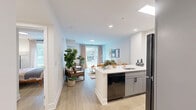 Located at 1 Hawaii Ave NW in Washington, DC, this one-bedroom, one-bathroom residence offers a thoughtfully laid-out floor plan that maximizes its compact footprint. Light-toned hardwood flooring flows throughout, creating a cohesive and airy aesthetic across every room.

The open-concept kitchen and living area serves as the heart of the home. The kitchen is outfitted with gray shaker-style cabinetry, stainless steel and black appliances, and a generous white quartz peninsula with seating for multiple guests — ideal for casual dining or entertaining. Recessed and linear lighting illuminates the workspace efficiently. The adjacent living room benefits from a large picture window that frames views of the neighborhood streetscape, filling the space with natural light.

The bedroom is a calm and comfortable retreat, featuring a sizable window overlooking greenery, light walls, and warm wood flooring that carries through from the main living area. The room comfortably accommodates a full-sized bed and additional furnishings.

The bathroom is finished with clean white subway tile in the shower-tub combo, a sleek gray vanity with a white countertop, black hardware accents, and modern tile flooring, delivering a polished, contemporary look. A hallway connects the rooms, adding privacy and a natural flow to the overall layout.