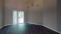 This two-floor home offers a thoughtfully designed layout across both levels, blending practical functionality with comfortable living spaces. The main level immediately impresses with soaring vaulted ceilings in the living area, which is bathed in natural light streaming through a large sliding glass door that opens to an outdoor view. Dark hardwood-style flooring extends throughout the main level, adding warmth and visual continuity.

A carpeted staircase with a classic wood railing and spindles connects the two floors, featuring an open railing design that enhances the sense of vertical space. The kitchen is equipped with warm wood cabinetry, white countertops, a double stainless steel sink, a dishwasher, and a window that brings in natural light.

The upper level hosts multiple carpeted bedrooms, each finished with neutral-toned walls and textured ceilings. The bedrooms feature built-in closets with shelving, providing ample storage. The bathroom is well-appointed with a wood-toned vanity, white countertop, a tub and shower combination, and dark hardwood-style flooring that mirrors the main level. Throughout the home, neutral gray and taupe tones create a calm, cohesive aesthetic suited for a variety of interior styles.