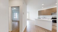 Located at 945 Reunion Ave in Langford, BC, this 2-bedroom, 1-bathroom unit offers a thoughtfully designed single-floor layout that maximizes functionality within a compact footprint. Light-toned wood-style flooring flows consistently throughout the space, complementing the clean white walls and creating a bright, cohesive aesthetic.

The kitchen is a standout feature, showcasing two-tone cabinetry with warm wood-grain upper cabinets and white lower cabinets, paired with white countertops and a central island that doubles as a breakfast bar. Stainless steel appliances, including a refrigerator, electric range, and dishwasher, complete this well-appointed cooking space. Recessed lighting adds a polished, modern touch overhead.

The open living area benefits from natural light streaming through large windows, contributing to an airy atmosphere. The primary bedroom offers a comfortable amount of space and includes access to a closet, while the second bedroom is bright with a large window. The bathroom features tile flooring and a clean, minimalist design consistent with the rest of the unit.

A hallway connects the key areas of the home, maintaining a smooth flow throughout. The overall design is clean, modern, and move-in ready, making this Langford residence a practical and stylish option.