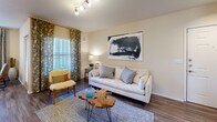 Located in Littleton, Colorado, this single-floor residence offers a well-organized and comfortable layout designed for everyday living. The living room serves as a welcoming central gathering space, featuring warm hardwood-style flooring, a track lighting fixture on the ceiling, and a large window dressed with patterned curtains that allow abundant natural light to fill the room. The kitchen is positioned adjacent to the living area in an open-concept arrangement, showcasing white cabinetry, a peninsula counter with ample workspace, and updated appliances. A dedicated dining nook sits nearby, benefiting from its own window with elegant drapery and providing an intimate setting for meals. The bedrooms are carpeted for comfort and warmth, each outfitted with windows that bring in natural light and views of the surrounding greenery. The primary bedroom includes direct access to an en-suite area, while additional bedrooms offer generous proportions suitable for varied uses. The bathrooms feature clean white tile surrounds with full tub and shower combinations. Throughout the residence, neutral warm tones on the walls create a cohesive and inviting ambiance, complemented by consistent flooring choices that tie the living spaces together seamlessly.
