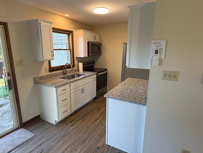 Modern kitchen features new cabinetry, granite countertops, and stainless steel appliances - 1004 Corbett St