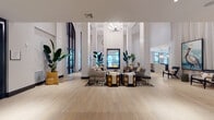 Located in Plantation, FL, the Remy Apartments clubhouse is a thoughtfully designed, single-floor amenity space that blends sophisticated design with welcoming comfort. The grand lobby immediately commands attention with its soaring double-height ceilings, structural columns, and an eye-catching modern chandelier. A sleek double-sided fireplace anchors the central lounge, which is furnished with curated seating arrangements set atop bold patterned area rugs, creating an inviting gathering space bathed in natural light from expansive black-framed floor-to-ceiling windows. Light-toned hardwood flooring runs throughout, offering a warm contrast to the crisp white walls accented with dark trim and molding. A dedicated lounge area features a striking dark paneled media wall with a large mounted television, complemented by sculptural décor and lush tropical greenery. The entry vestibule offers an airy, light-filled welcome with wraparound windows overlooking the lush exterior grounds. A private dining room provides a more intimate setting, complete with a statement botanical wallcovering, a linear pendant light fixture above a dark dining table, and a wall-mounted display screen — ideal for private events or meetings. Throughout the space, curated artwork, large potted tropical plants, and eclectic furnishings contribute to a refined yet relaxed atmosphere.