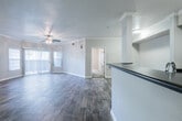 This single-floor residence offers a well-designed layout that balances functionality and comfort throughout its living spaces. The open-concept living area serves as the heart of the home, featuring rich wood-look flooring, crown molding, and a ceiling fan with light fixture. A large window with vertical blinds allows natural light to fill the room, creating a bright and welcoming atmosphere.

The kitchen is efficiently designed with white cabinetry, dark countertops, and stainless steel appliances including a refrigerator, range, microwave, and dishwasher. Wood-look flooring continues through the kitchen, which connects seamlessly to the rest of the unit. A peninsula with a sink provides additional workspace and separation from the main living corridor.

The bedrooms are finished with plush carpet and feature convenient access to hallway spaces. A generously sized walk-in closet is outfitted with multiple wire shelving units and hanging rods, offering ample storage. The bathroom is well-appointed with white cabinetry, a dark countertop, a wide vanity mirror, and wood-look flooring, with a separate tiled shower area. A dedicated laundry room houses a full-size washer and dryer beneath overhead white cabinetry, adding to the unit's practical storage options. Textured walls and ceilings are consistent throughout the space.