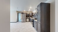 Located at 360 32nd Ave W in West Fargo, ND, this well-designed 2-bedroom, 2-bathroom unit offers a thoughtful single-level layout with contemporary finishes throughout. The kitchen is a standout feature, showcasing dark-toned shaker-style cabinetry, a decorative tile backsplash, light quartz countertops, open wood shelving, and a full suite of stainless steel appliances including a refrigerator, range with hood vent, microwave, and dishwasher. Marble-look luxury flooring runs seamlessly through the kitchen and into the open living area, which is bathed in natural light from large black-framed windows and a sliding glass door that leads to a private balcony with urban views. The bedrooms are bright and comfortable, with the primary bedroom featuring a ceiling fan, dual windows with roller shades, and access to a dedicated walk-in closet outfitted with wire shelving systems. The two bathrooms are clean and functional, one featuring a walk-in shower with a built-in bench and the other a soaking tub, both with dark wood vanities and marble-look tile flooring. Two closets provide ample storage throughout the unit, completing this practical and modern living space.