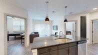 Located at 13060 Clemson Blvd in Seneca, SC, this single-floor, 4-bedroom, 4-bathroom unit offers a well-designed layout with modern finishes throughout. The open-concept kitchen and living area serves as the heart of the unit, anchored by a large granite-topped island with an undermount sink and pendant lighting. White upper cabinetry contrasts with dark lower cabinets, and stainless steel appliances — including a refrigerator, range, and microwave — complete the kitchen. A dedicated laundry area is conveniently accessible from the kitchen. The living room features wood-look luxury vinyl flooring, a ceiling fan, and expansive sliding glass doors dressed with vertical blinds that allow abundant natural light and outdoor views. Each of the four bedrooms is bright and functional, with ceiling fans, natural light from windows with blinds, and dedicated closets. The primary bedroom includes a walk-in closet and a private en-suite bathroom. The bathrooms are finished with granite-topped vanities featuring dark cabinetry, wood-look flooring, and tub-shower combinations. With five closets total and a clean, contemporary aesthetic, this unit offers practical, comfortable living throughout.