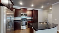 This well-appointed single-story residence in Little Rock, Arkansas, offers a thoughtfully designed layout that maximizes both comfort and functionality. Rich hardwood-style flooring flows throughout the home, complemented by crown molding and recessed lighting that lend a polished, cohesive aesthetic.

The open-concept kitchen is a standout feature, showcasing floor-to-ceiling rich mahogany cabinetry, sleek dark granite countertops, and a classic white subway tile backsplash. A central island with an undermount sink provides additional prep and dining space, while a full suite of stainless steel appliances — including a gas range, built-in microwave, and French door refrigerator — elevates the culinary experience.

The living area is bright and welcoming, featuring a ceiling fan, recessed lighting, and elegant French doors that invite natural light and offer access to the outdoors. Crown molding frames the space with a refined touch.

The bathroom is a serene retreat, appointed with a deep soaking tub surrounded by granite-style surround tile, a separate glass-enclosed walk-in shower, and warm wood-tone flooring. The dual bathing options make this space both practical and luxurious.

Overall, the residence combines modern finishes with classic architectural details, creating a comfortable and visually appealing home in the heart of Little Rock.