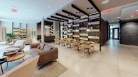 Located at 1441 U Street in Washington, DC, this contemporary amenity floor offers a thoughtfully designed communal environment that blends modern aesthetics with functional living spaces. The expansive lobby lounge features large-format porcelain tile flooring, bold black ceiling beam accents, and floor-to-ceiling windows that flood the interior with natural light while framing views of a landscaped outdoor courtyard. Comfortable seating arrangements with neutral-toned sofas and accent chairs create an inviting atmosphere for relaxation. A dedicated dining and co-working area is defined by a dramatic vertical living green wall partitioned by black metal framing and pendant lighting, alongside light wood tables and chairs. An integrated media lounge provides a wall-mounted television and additional seating, ideal for casual gatherings. The grooming suite features a glass-enclosed shower, mosaic tile walls, a floating vanity with a clean white countertop, under-cabinet lighting, and rustic wood-plank accent shelving. Outside, a private courtyard offers artificial turf, raised planting beds, mature trees, a wood-paneled privacy wall, and bench seating — providing a peaceful urban retreat. Together, these spaces deliver a polished, resort-inspired experience in the heart of Washington, DC.