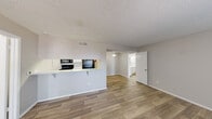 Located at 700 S Fourth St in Waco, TX, this single-floor, 2-bedroom, 2-bathroom unit offers a functional and comfortable layout designed for everyday living. The open-concept living and kitchen area serves as the heart of the home, featuring durable wood-look flooring, neutral gray-toned walls, and a textured ceiling throughout. The living room is highlighted by a classic fireplace with a white mantle and a large window fitted with blinds, filling the space with natural light. The kitchen is positioned behind a peninsula counter with a breakfast bar overhang, equipped with a black electric range, over-the-range microwave, white cabinetry, and speckled countertops — all accessible from the main living area. Both bedrooms are carpeted and well-proportioned, with the primary bedroom offering a dedicated ceiling fan and a window with outdoor views. Each bathroom features wood-look flooring, a tub-shower combination with white tile surround, and a vanity with speckled countertops and a large mirror. A dedicated entrance and closet round out the layout. The unit's clean, neutral palette and practical design make it a comfortable and move-in-ready home.