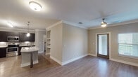 This single-story residence in Spring, Texas offers a thoughtfully designed layout with two bedrooms and two bathrooms. Crown molding runs throughout the main living areas, complementing warm neutral tones and wood-look flooring that extends across the open-concept living and dining spaces. A ceiling fan and glass-paneled door in the living area allow natural light to filter in, creating a bright and welcoming atmosphere.

The kitchen is a standout feature, showcasing dark espresso cabinetry, granite countertops, a subway tile backsplash with under-cabinet lighting, and a full suite of stainless steel appliances. A large island with a single-basin sink and pendant lighting above provides both additional workspace and a natural gathering point.

The bedrooms are carpeted for comfort, each offering ceiling fans and windows with outdoor views. Built-in shelving near the main living area adds functional storage and display space. The primary bathroom includes a framed mirror, granite-topped dark vanity, and a glass-enclosed shower. The second bathroom mirrors the same refined aesthetic with a granite vanity and a tub-shower combination. An entry foyer with a walk-in closet completes this well-organized home.