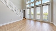 Located at 1000 Central Ave in Charlotte's vibrant 28204 corridor, this two-story, one-bedroom, one-bathroom home offers a well-designed layout across two evenly balanced floors. The main level features an open-concept kitchen and living area bathed in natural light from dramatic floor-to-ceiling windows that stretch across the full width of the space, flooding the interior with sunlight and offering views of the surrounding neighborhood. The soaring double-height ceilings in the living area create an airy, expansive atmosphere, complemented by light-toned hardwood-style flooring throughout. A white staircase with classic balusters connects the two floors with architectural elegance. The kitchen is outfitted with stainless steel appliances including a refrigerator, range, microwave, and dishwasher, set against crisp white cabinetry and a clean subway tile backsplash. Upstairs, the bedroom features vaulted ceilings, hardwood-style floors, a ceiling fan, and a dedicated closet, offering a comfortable private retreat. The bathroom showcases a full soaking tub surrounded by floor-to-ceiling white subway tile and brushed gold fixtures, combining a clean aesthetic with a touch of warmth. Track lighting and neutral wall tones complete the home's modern, move-in-ready appeal.