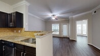 Located at 3323 McCue Rd in Houston's 77056 corridor, this two-bedroom, one-bathroom residence offers a well-designed single-floor layout that makes efficient use of its space. Dark hardwood-style flooring runs throughout, providing a cohesive and contemporary look across every room.

The open-concept kitchen flows directly into the living area, making it ideal for both everyday living and entertaining. The kitchen is appointed with dark espresso cabinetry, granite-style countertops, a mosaic tile backsplash, and a full suite of stainless steel appliances including a refrigerator, range, and over-the-range microwave. A breakfast bar with a built-in sink serves as a natural divider between the kitchen and living space. The living room benefits from crown molding, a ceiling fan, and windows that invite natural light.

The primary bedroom is a generously sized retreat featuring a bay window configuration, a ceiling fan, and ample natural light. The second bedroom includes a closet with built-in shelving. The bathroom offers a tiled tub-shower combination with a dark vanity. A dedicated laundry closet in the hallway houses a full-size washer and dryer. Two hallways and an additional closet round out the thoughtfully arranged floor plan.