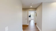 Located at 95 Cedar St in Providence, Rhode Island, this single-floor, three-bedroom, two-bathroom home offers a well-designed layout with a consistent modern aesthetic throughout. Wood-style flooring runs seamlessly across every room, complemented by neutral warm-gray walls, crisp white trim, and recessed lighting that keeps the interior bright and welcoming.

The spacious primary bedroom is generously sized, featuring dual windows fitted with white horizontal blinds that allow natural light to filter in while offering views of the surrounding neighborhood. A double sliding closet provides ample storage, and recessed ceiling lights complete the clean, functional design. The two additional bedrooms maintain the same finishes, each with windows that invite natural light and easy access to the hallway.

Both bathrooms are finished to a high standard. One features a sleek walk-in glass shower with chrome fixtures and a white vanity topped with a backlit mirror, while the second bathroom offers a vanity with a crisp white countertop and a matching illuminated mirror. Wood-style flooring carries through both bathrooms, maintaining the home's cohesive design language.

A connecting hallway links the rooms efficiently, reinforcing the practical and open flow of the floor plan. Overall, this home presents a clean, modern, and move-in-ready living environment.