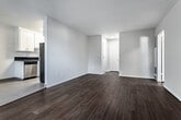 Located at 625 N Sycamore Ave in the heart of Los Angeles, this single-floor unit offers a well-organized layout with consistent design details throughout. Rich, dark hardwood flooring flows seamlessly across the living areas and bedrooms, creating a warm and cohesive aesthetic against the neutral, light-toned walls.

The open living and dining area is bright and airy, benefiting from natural light that enters through a sliding glass door fitted with vertical blinds that lead to an outdoor view. A wall-mounted air conditioning unit provides climate control. The space connects naturally to a secondary area with a ceiling fan and additional window, enhancing airflow and light.

The galley-style kitchen is efficiently designed, featuring dark granite countertops, white cabinetry, light tile flooring, a stainless steel gas range, and a full-size stainless steel refrigerator. A separate door within the kitchen provides additional access or storage.

The bedrooms continue the dark hardwood flooring theme and are well-lit by large windows with horizontal blinds. One bedroom includes a mirrored sliding-door closet, while others offer ceiling fans and generous wall space.

The bathrooms are a standout feature, finished with white subway tile and accented by decorative blue and green mosaic tile borders. One bathroom includes a soaking tub with a glass sliding door enclosure, while another offers a walk-in shower stall, both reflecting a clean, updated finish.