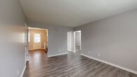Located at 2979 Columbus St. in Grove City, Ohio, this single-floor, two-bedroom, one-bathroom unit offers a practical and functional layout. The living room greets residents with neutral gray walls and durable wood-look vinyl plank flooring that flows throughout the main living areas, creating a cohesive and clean aesthetic. Natural light filters in through windows, brightening the open feel of the space.

The kitchen is a standout feature, equipped with white shaker-style cabinetry, a classic subway tile backsplash, light granite-look countertops, a stainless steel dishwasher, a range, and a full-size stainless steel refrigerator. A rear entry door and window provide additional light and convenient access.

Both bedrooms are finished with neutral carpet and are served by baseboard heating. The primary bedroom includes a wall-mounted air conditioning unit for individual climate control. Three closets throughout the unit offer generous storage options.

The bathroom is appointed with a full tub and shower combination, a white vanity, and vinyl plank flooring, maintaining the clean, consistent style found throughout the home. Baseboard heating is present throughout, ensuring year-round comfort in this efficiently designed Grove City residence.