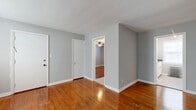 Located at 13542 Detroit Avenue in Lakewood, Ohio, this one-bedroom, one-bathroom unit offers a thoughtfully organized single-floor layout. Warm, richly toned hardwood floors run throughout the main living areas, reflecting natural light and lending a timeless character to the space. The combined dining and living room serves as the heart of the unit, featuring soft gray walls, clean white trim, and two windows framing a classic cast-iron radiator — a charming nod to the building's heritage. A hallway connects the living area to the remaining rooms, maintaining a logical and efficient flow. The bedroom is a comfortable retreat equipped with a ceiling fan, a window for natural light and ventilation, and access to multiple closets, offering generous storage for its size. The kitchen is well-appointed with white cabinetry, a subway tile backsplash, dark granite-style countertops, a stainless steel sink, and a bright window above the counter. A dedicated pantry adds practical storage. The bathroom features classic white subway tile surrounding a tub/shower combination with a frosted privacy window. Cast-iron radiators throughout the unit speak to the building's enduring construction quality, while the consistent gray-and-white palette creates a cohesive, clean aesthetic throughout.