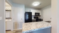 Located at 1919 Georgesville Square in Galloway, Ohio, this single-floor residence offers a clean, modern aesthetic throughout its thoughtfully designed layout. The kitchen serves as a focal point of the unit, showcasing a granite-topped breakfast bar peninsula that opens to the living area, creating a seamless flow between spaces. White shaker-style cabinetry provides ample storage, while black appliances — including a full-size refrigerator, electric range, and built-in microwave — add a bold contrast against the light countertops and soft gray walls. Light wood-style vinyl plank flooring runs throughout the main living and kitchen areas, contributing to a cohesive and easy-to-maintain interior. The bedroom is a well-sized, comfortable space featuring durable wood-tone laminate flooring, a ceiling fan with integrated lighting, and a window that allows natural light to filter in. The bathroom is efficiently appointed with a full tub-shower combination, a white vanity with an integrated sink, and a framed mirror, all set atop matching wood-style flooring. Neutral gray tones used consistently across the unit create a calm and versatile atmosphere suited to a variety of furnishing styles.