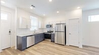 Located at 13241 Hero Way West in Leander, TX, this two-story home offers a thoughtfully designed layout spread across two well-proportioned floors. The main level features an open-concept kitchen and living area bathed in natural light from multiple windows. The kitchen is outfitted with two-tone cabinetry — white upper cabinets paired with slate-blue lower cabinets — granite-look countertops, a subway tile backsplash, and a full suite of stainless steel appliances including a refrigerator, electric range, microwave, and dishwasher. Light wood-look flooring runs throughout the main level, complementing the bright, white walls. A ceiling fan anchors the living area, which offers direct access to an exterior door. A half bathroom is conveniently located on the main floor. Upstairs, the spacious primary bedroom features plush carpeting, a large window for natural light, and elevated ceilings that lend a sense of openness. The primary bathroom includes a glass-enclosed shower, a vanity with granite-look countertops and blue-gray cabinetry, and wood-look flooring. A dedicated closet and an in-unit stacked washer and dryer complete the upper level, adding practical convenience to this well-appointed home.