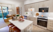 This contemporary 550 square foot apartment in Irvine, CA, maximizes space with a thoughtful single-floor layout. The lone bedroom, measuring 150 square feet, features a serene ambiance with textured wallpaper, a plush bed, and ample natural light from large windows. The living area boasts a curved tan sofa, modern art pieces, and a sleek entertainment unit, all bathed in natural light from a balcony door. The kitchen impresses with light wood cabinetry, stainless steel appliances, and a compact island, perfect for casual dining. Two full bathrooms offer luxury and convenience, with one showcasing a spacious glass-enclosed shower. Throughout the apartment, a neutral color palette with warm accents creates a cohesive and inviting atmosphere. Despite its modest size, the space feels open and airy, thanks to its clever design and high-quality finishes.
