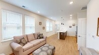 This single-story home in Meridianville, Alabama offers a thoughtfully designed layout across two bedrooms and two bathrooms. The open-concept living area and kitchen form the heart of the home, connected by light wood-tone flooring that runs throughout. The living room features multiple windows with white blinds, recessed lighting, and a front entry door with glass panels that invite natural light into the space.

The kitchen is anchored by a peninsula island with a white quartz countertop, an undermount sink, and pendant lighting overhead. Warm-toned cabinetry lines the walls alongside a full suite of stainless steel appliances, including a refrigerator, range, and microwave. Ample upper cabinet storage completes the functional cooking space.

The primary bedroom accommodates a queen or larger bed comfortably, features a ceiling fan, and connects directly to an en-suite bathroom. The bathroom includes a dark wood vanity with a white countertop, a lighted mirror, and a shower-tub combination with a window for natural ventilation. The second bedroom also features a ceiling fan and provides access to an in-unit stacked washer and dryer. Both bathrooms maintain consistent, clean finishes throughout.