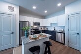 This contemporary 1010 square foot apartment offers a harmonious blend of style and functionality. The open-concept layout maximizes space, featuring a well-appointed kitchen with stainless steel appliances, granite countertops, and a convenient island with seating. The living area is bathed in natural light from large windows, complemented by a modern ceiling fan. Two bedrooms, including a 180 square foot primary suite, provide comfortable sleeping quarters. Both bathrooms boast sleek designs with marble-look tiles and spacious vanities. The apartment includes two closets for ample storage, one being a walk-in. Hardwood-style flooring runs throughout, enhancing the modern aesthetic. Thoughtful touches like stylish light fixtures, contemporary artwork, and a carefully curated color palette in cool blues and warm neutrals create a cohesive and inviting atmosphere. This turnkey residence in Domain Huntsville is perfect for those seeking a sophisticated urban lifestyle with all the comforts of home.