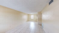 Located at 910 S Volusia Ave in Orange City, Florida, this single-story, one-bedroom, one-bathroom unit offers a practical and well-organized layout. Light tile flooring runs throughout the entire space, contributing to a clean, cohesive aesthetic.

The combined living and dining area forms the heart of the unit, offering an open feel with warm, cream-colored walls, a textured ceiling, and natural light streaming in through windows. The front entry door features glass panel accents, further brightening the space.

The kitchen is efficiently designed in a U-shaped configuration, featuring rich dark wood cabinetry, white countertops, a double-basin sink, an electric range, and a full-size refrigerator. A drop-ceiling with panel lighting adds functionality. A pass-through counter window connects the kitchen directly to the dining area, enhancing the open flow between spaces.

The bedroom is a comfortable size, with a large louvered bifold closet door providing generous storage. A window overlooks the exterior, allowing natural light in. The unit also includes four closets in total, providing exceptional storage throughout.

The bathroom is well-appointed with a wide vanity, ample cabinet storage, a wall mirror, lighted vanity fixture, toilet, and a tub/shower combination. A frosted window provides natural light while maintaining privacy.