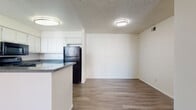 This single-floor residence offers a well-organized layout with consistent wood-look flooring running throughout, creating a cohesive and easy-to-maintain interior. The kitchen is designed for functionality, featuring white cabinetry, dark granite-style countertops, and a full suite of black appliances including a refrigerator, electric range, built-in microwave, and dishwasher. A peninsula counter separates the kitchen from the adjacent dining and living areas, promoting an open, connected feel.

The living room is generously sized, featuring a ceiling fan with light fixture and a sliding glass door with vertical blinds that allows natural light to flow in while providing access to an outdoor area. Textured ceilings are present throughout the home.

The bedrooms are well-proportioned, each offering wood-look flooring, neutral walls, and closets with sliding doors and built-in shelving for ample storage. One bedroom includes a window with blinds that brings in natural daylight. The layout also shows a bedroom with convenient direct access to a bathroom.

Both bathrooms are clean and bright, each offering a full tub-shower combination, a toilet, and a vanity with white cabinetry and dark countertops. One bathroom features a large mirror above the vanity, enhancing the sense of space. The overall ambiance of the unit is clean, neutral, and move-in ready.