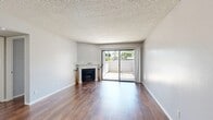 This single-story, 3-bedroom, 2-bathroom home offers a practical and comfortable layout with consistent rich hardwood-style flooring throughout. The living room serves as the heart of the home, highlighted by a classic corner fireplace and a sliding glass door that opens to an outdoor patio, allowing natural light and views of mature palm trees to fill the space. A textured ceiling adds a traditional touch throughout the unit.

The galley-style kitchen is well-equipped with white cabinetry, granite-style countertops, a gas range, dishwasher, and a built-in skylight panel overhead, creating a bright and efficient cooking environment. The kitchen opens toward the main living area, enhancing the sense of flow.

The primary bedroom is generously sized and features its own access to a dedicated walk-in closet outfitted with multi-tier shelving for ample storage. A second bedroom also benefits from sliding glass door access, bringing in additional natural light. Both bedrooms continue the warm hardwood-style flooring found throughout the home.

The bathrooms are clean and functional, featuring granite-style countertops, white cabinetry, large mirrors, and a tub/shower combination. Neutral gray walls provide a modern, move-in-ready aesthetic throughout this efficiently designed home.