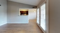This single-floor residence offers a thoughtfully designed layout with a clean, neutral palette throughout. The open living area is anchored by warm-toned hardwood-style flooring and vaulted ceilings that enhance the sense of space. A set of French doors floods the room with natural light and provides access to the outdoors, while a pass-through window connects the living area seamlessly to the kitchen. The galley-style kitchen is well-equipped, featuring dark espresso cabinetry, stainless steel appliances including a refrigerator, microwave, and range, complemented by a mosaic tile backsplash and light countertops. The entryway welcomes residents with a coat closet and convenient storage, transitioning smoothly into the main living spaces. Bedrooms are finished with plush carpeting and ceiling fans, creating a comfortable retreat. Each bedroom benefits from natural light via blinded windows, and walk-in closets provide generous storage. The bathroom is appointed with a angular dark wood vanity, white countertops, a large mirror with a multi-bulb vanity light fixture, and a tiled shower-tub combination. Consistent hardwood-style flooring runs through the common areas, unifying the overall aesthetic of this well-maintained residence.