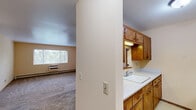 Located at 719 N Court St in Rockford, Illinois, this unit offers three bedrooms and two bathrooms across a single floor. The layout is efficient and functional, with soft neutral tones and warm beige walls throughout that create a cohesive, inviting atmosphere.

The spacious primary bedroom is generously sized, featuring carpet flooring, a baseboard heating system, a large window that allows natural light and views of the surrounding trees, and a wide louvered bi-fold closet for ample storage. The additional bedrooms are similarly appointed with carpet, baseboard heat, and louvered bi-fold closet doors.

The living area is open and bright, highlighted by a ceiling fan with light fixture and a distinctive pass-through window connecting to the kitchen, complete with wood-framed shutters and cabinetry. This architectural detail adds charm while maintaining an open feel between the two spaces.

The full bathroom features classic white subway tile surrounding the tub-shower combination, mosaic tile flooring, and a pedestal sink. A second bathroom provides additional convenience. Throughout the unit, warm-toned carpet, clean white ceilings, and wood-accented doors and trim contribute to a consistent, comfortable aesthetic.
