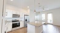 Located at 9105 Tredinick Pkwy in Jacksonville, FL, this single-story, 2-bedroom, 1-bathroom home offers a thoughtfully designed layout with modern finishes throughout. The open-concept living, dining, and kitchen area forms the heart of the home, with warm hardwood-style flooring, recessed lighting, and a ceiling fan creating a bright and welcoming atmosphere. The kitchen is outfitted with white shaker-style cabinetry, granite countertops, a central island with pendant lighting, and a full suite of stainless steel appliances. Natural light pours in through multiple windows, enhancing the airy feel of the shared living space. Both bedrooms feature plush carpet flooring, ceiling fans, and generous windows that allow ample natural light. The primary bedroom is a comfortable retreat with notable square footage and access to a spacious walk-in closet equipped with wire shelving. The bathroom is clean and well-appointed, featuring a tiled tub-shower combo, granite vanity, and wood-style flooring. Additional spaces include an entrance, hallway, laundry area, and a covered porch overlooking a landscaped community setting with neighboring homes. The home also includes a dedicated closet for added storage convenience.