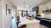 Located on East Colfax Avenue in Denver's Congress Park neighborhood, this one-bedroom, one-bathroom unit offers a thoughtfully designed single-level layout with contemporary finishes throughout. Light wood-tone flooring runs continuously across the space, creating a cohesive and clean aesthetic.

The open-concept kitchen and living area serves as the heart of the unit. The kitchen is outfitted with two-tone cabinetry — light upper cabinets paired with dark lower cabinets — complemented by a white quartz countertop, a subway tile backsplash, stainless steel appliances, a built-in wine cooler, and a large central island with seating. Pendant lighting above the island adds a refined touch. The living area flows naturally from the kitchen and features large windows and sliding glass door access to a private balcony, allowing for ample natural light and outdoor views.

The bedroom is a comfortable retreat with large sliding glass doors that bring in additional natural light and neighborhood views. A dedicated closet provides organized storage. The bathroom features a sleek, modern design with dark cabinetry, a white quartz vanity, and a glass-enclosed walk-in shower with large-format tile and matte black fixtures. Throughout the unit, neutral wall tones and wood flooring contribute to a warm, contemporary ambiance.