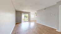 This two-bedroom, one-bathroom apartment at Addison Apartments at the Park spans 820 square feet of well-organized living space on a single floor. Wood-style laminate flooring runs consistently throughout the unit, lending a warm and cohesive aesthetic to each room. The open living room is spacious and bright, featuring neutral gray walls, a textured ceiling, and a sliding glass door that opens to a private balcony with outdoor views. The adjacent kitchen is outfitted with warm-toned amber cabinetry, light countertops, a built-in range, dishwasher, and a pass-through counter that connects to the living area, enhancing the open feel. The primary bedroom measures 200 square feet and includes access to a dedicated closet with built-in shelving rods, providing ample storage. The second bedroom is well-proportioned and features a large window with natural tree views. The shared bathroom includes a single-sink vanity with amber cabinetry, a wall mirror, and a full tub-shower combo with white tile surround. A hallway connects all rooms efficiently, completing the functional layout of this apartment.