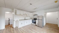 Located at 1305 Washington Ave in Bay City, Michigan, this two-bedroom, one-bathroom home offers a thoughtfully updated interior spread across a single floor. Light wood-grain vinyl flooring runs throughout the space, creating a cohesive and bright aesthetic from room to room.

The kitchen is a standout feature, finished with crisp white shaker cabinetry, granite-look countertops, and stainless steel appliances including a refrigerator and electric range. The open layout connects the kitchen to the living area, making the combined space functional and easy to navigate.

The primary bedroom is generously sized, offering ample room for furnishings, and includes a ceiling fan for added comfort. A wall-mounted PTAC heating and cooling unit provides climate control. The second bedroom is well-proportioned, featuring a built-in closet with bifold doors and a window that allows natural light to enter.

The bathroom is cleanly finished with light flooring and simple, modern fixtures. A dedicated laundry room houses a full-size washer and dryer, adding convenience to daily living. The home also includes a closet for additional storage. White walls throughout the space maintain a bright, neutral backdrop that suits a variety of interior styles.