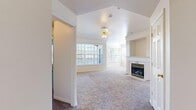 Located at 842 W 880 N in Orem, Utah, this single-floor, 2-bedroom, 2-bathroom home offers a thoughtfully designed layout across a comfortable footprint. The living room serves as the centerpiece of the home, featuring plush carpet, crown molding, a ceiling fan, and a classic fireplace with a white mantel and built-in shelving niche. Large windows along two walls flood the space with abundant natural light, creating a bright and welcoming atmosphere. The kitchen is equipped with warm-toned cabinetry, generous counter space, tile flooring, and stainless steel appliances including an electric range. Both bedrooms are carpeted and well-lit, with ceiling fans and windows that bring in natural light. The spacious primary bedroom includes a walk-in closet outfitted with wire shelving and additional storage racks. A second walk-in closet provides further organizational space. Both bathrooms are finished with tile flooring and vanities with ample counter space; one features a full tub-shower combination with large-format wall tile and a decorative mosaic accent border. The dedicated laundry room accommodates a full-size washer and dryer and includes overhead wire shelving. Two hallways connect the rooms efficiently throughout the home.