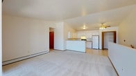 This single-floor residential unit offers a functional and well-organized layout with a bright, open feel throughout. The living area is generously sized, featuring plush wall-to-wall carpeting, a vaulted ceiling with a ceiling fan, and baseboard heating. A sliding glass door leads to a private balcony, allowing natural light to fill the space, while additional windows provide views of the surrounding neighborhood.

The kitchen is efficiently designed in a U-shaped configuration, outfitted with white cabinetry offering ample storage, neutral laminate countertops, tile flooring, and a full suite of appliances including a range, dishwasher, and refrigerator. A peninsula counter connects the kitchen to the living area, creating a convenient open flow between the two spaces.

The bedrooms are carpeted and well-lit by windows with exterior views. Each room features baseboard heating, and at least one bedroom includes a sliding-door closet with mirrored panels, providing practical storage. Both bathrooms are finished with tile flooring and include vanities with storage — one features a large lighted mirror above the sink, adding brightness to the space.

Overall, the unit maintains a clean, neutral aesthetic with warm wood trim accents, making it a versatile and move-in-ready space.