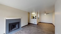 This single-floor residence offers a thoughtfully designed layout that balances comfort and functionality. The open-concept living and dining area is finished with durable wood-look flooring and anchored by a tile-surround fireplace, creating a welcoming focal point. A ceiling fan adds practical comfort to the space. The adjacent kitchen features a pass-through counter design, white cabinetry, stainless steel appliances including a refrigerator, range, and microwave, and dark countertops — all accounted for within a compact, efficient footprint.

The two bedrooms are carpeted for warmth and comfort, each benefiting from natural light through blinded windows. One bedroom includes a built-in closet and direct access to an en-suite bathroom, while the other is served by a second full bathroom. Both bathrooms are finished with wood-look tile flooring, white vanity cabinetry, dark stone-style countertops, and large mirrors. Baseboard heaters in the bedrooms provide supplemental warmth. The neutral color palette throughout — warm beige walls, white trim, and dark baseboards — lends the space a clean, cohesive aesthetic that is both practical and inviting.